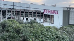 白い外壁が大きく破損して内部が見えている建物。AEON MALLとピンクの文字が壁に掲示されている