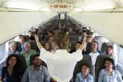 Una azafata muestra dónde están las salidas de emergencia en un avión.
