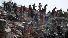 Personas buscan supervivientes mientras otras intentan rescatar pertenencias de un edificio colapsado tras un terremoto en Catia La Mar, estado de La Guaira, el 25 de junio de 2026.