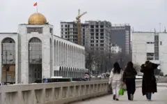 Un edificio con una cúpula dorada y la bandera de Kirguistán.