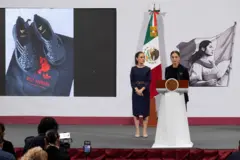 A vice-ministra de Desenvolvimento Cultural do México, Marina Núñez Bespalova, fala em um púlpito no palco, com os tênis da Adidas expostos ao fundo e repórteres em primeiro plano