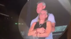 A man and woman are seen embracing on a jumbo screen at a Coldplay concert 