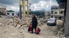 Lübnan'da bir kadın yıkıntılar arasında yürüyor. 