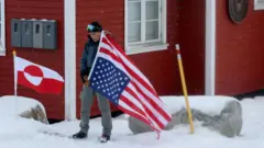 Osoba, która nie chciała podać swojego nazwiska, protestuje przed Konsulatem Amerykańskim przeciwko – jak twierdzi – „zagrożeniu możliwością aneksji Grenlandii przez USA”, 14 marca 2025 roku w Nuuk, Grenlandia. Prezydent USA Donald Trump wielokrotnie zapowiadał przejęcie Grenlandii przez Stany Zjednoczone.