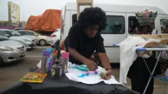 Habarata as she dey design her cloth for road 