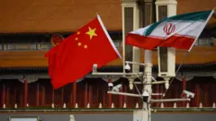 北京天安門廣場上電燈柱懸掛中國（中）與伊朗（右）國旗（資料圖片）