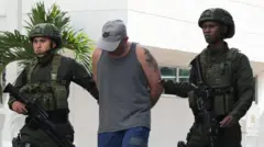 Homemgloboesporte com globoesporte comcabeça baixa sendo conduzido por 2 policiais 