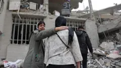 People gather next a damaged building in the aftermath of a strike, amid the U.S.-Israeli conflict with Iran, in Tehran, Iran, March 12, 2026