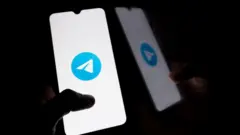 Two hands operating phones with Telegram 