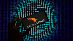 Un collage de una mano sosteniendo un móvil con el logo de Crowdstrike con un fondo de ceros y unos.