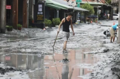 A resident walks with a shovel along a mud-covered road in Hualien on September 24, 2025, following the bursting of a barrier lake during the passing of Super Typhoon Ragasa.