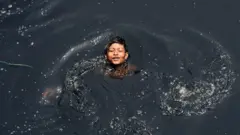 Un niño indio nada en el contaminado río Yamuna en medio de un aumento de las temperaturas en Nueva Delhi el 9 de mayo de 2017.