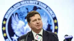 Jay Clayton, procurador federal do Distrito Sul de Nova York, fala em entrevista coletiva de terno escuro, ao lado de microfones de órgãos de imprensa dos Estados Unidos, com o selo do Departamento de Justiça americano atrás dele