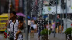 Uma mulher se refresca em uma fonte no centro de Porto Alegre, Brasil, em 15 de dezembro de 2023, quando uma onda de calor atingiu o Rio Grande do Sul,