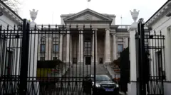 Ambasada Rusiei din Polonia - o clădire neoclasică impunătoare, care are o poartă masivă din fier forjat în față. O mașină neagră se vede trecând prin poarta deschisă. 
