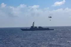 Navio americano no mar e um helicóptero no céu