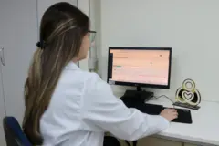 Farmacêutica usando o sistema da NoHarm no computador