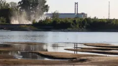reka i korito iza koje se vidi nuklearna elektrana