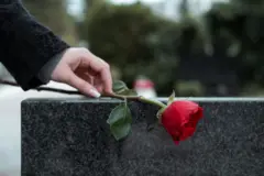 Uma mulher coloca uma flor sobre um túmulo.