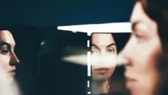 یوه ښځه چې غټې سترګې لري، هنداره کې ګوري. 