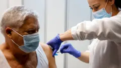 мушкарац добија вакцину, носи маску 