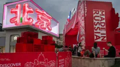 Os caracteres chineses que formam o nome de Pequim aparecem em um grande telão durante um evento de promoção de produtos da campanha "Made in Russia" e das relações entre China e Rússia, em um shopping center em Pequim, na China
