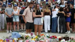 Люди у мемориала рядом с местом, где произошла стрельба