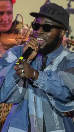 A man wears a blue jacket and holds a microphone