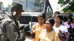 ශ්‍රී ලංකා යුධ හමුදා සොල්දාදුවෙකු බස් රථයක මඟීන් පරීක්ෂා කරමින්