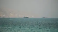 崖を背に船が2隻、洋上に浮いている