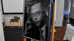 Um retrato em preto e branco emoldurado mostra o médico egípcio Mohamed Helmy usando camisa listrada e gravata