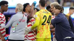 Jogadores dos EUA bebem perto da linha lateral e ouvem as instruções do técnico Mauricio Pochettino durante a pausa para hidratação na partida de abertura da Copa do Mundo de 2026 contra o Paraguai