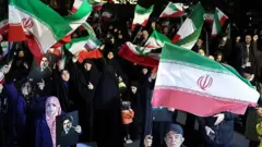 Pessoas acenam com bandeiras nacionais e seguram retratos do líder supremo do Irã, Mojtaba Khamenei, enquanto marcham em apoio às forças armadas iranianas no centro de Teerã, em 25 de março de 2026.