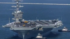 یک ناو بزرگ آمریکایی با خدمه روی عرشه و دو کشتی در اطرافش