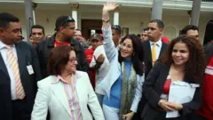 Cilia Flores, rodeada de personas saluda levantando un brazo en alto.