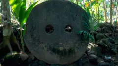 Disco de piedra con dos hoyos en medio del bosque