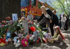 Українці несуть квіти та м’які іграшки до місця російського удару по житловому району в Києві 15 травня 2026 року. Мер Києва оголосив 15 травня днем жалоби за жертвами російської комбінованої атаки 14 травня.