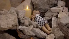مجسم الطفل يسوع المسيح بالكوفية الفلسطينية وضعت بدلاً من زينة عيد الميلاد بين الركام.