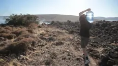 Kurak bir toprak üzerinde omzunda damacanayla su taşıyan adam - Çeşme, İzmir, 3 Temmuz 2025