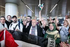 مشاركون في مسيرة غزة يرفعون علامة النصر لدى مغادرتهم من هولندا إلى مصر، في 11 يونيو/حزيران 2025. 
