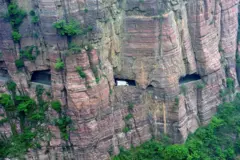Parede rochosa de uma montanha com buracos através dos quais você pode ver um caminhão