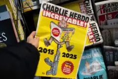 Edição da revista Charlie Hebdo, com as datas 2015 e 2025, e uma pessoa sentada na ponta dee uma arma com a revista abertapixbet fantasy 5mãos