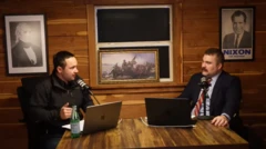 Dois homens sentados frente ao microfone e computadores, com imagens consideradas patrióticas ao fundo. Entre elas, inclui-se uma cópia de um famoso quadro de George Washington durante a Guerra da Independência dos Estados Unidos e fotos dos ex-presidentes Richard Nixon e James Polk.