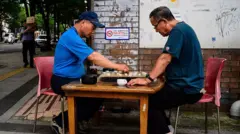 Dois homens jogam Janggi, às vezes chamado de xadrez coreano, em uma rua de Seul, em 1º de julho de 2025.