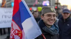 momak sa šajkačom, drži zastavu Srbije na studentskom protestu