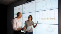 Dos expertos hablan frente a una pantalla con información fenómica