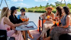 Mulheres sentadas em barco tomando drinks