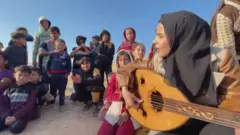 رؤيا حسونة وهي تعزف العود للأطفال في مخيم في رفح