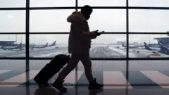 Мужчина с чемоданом идет по галерее в аэропорту. На фоне видны самолеты "Аэрофлота"