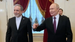 Kravatsız İranlı diplomat ile Putin yan yana yürüyor. Rus lider elini yol gösterir gibi uzatmış